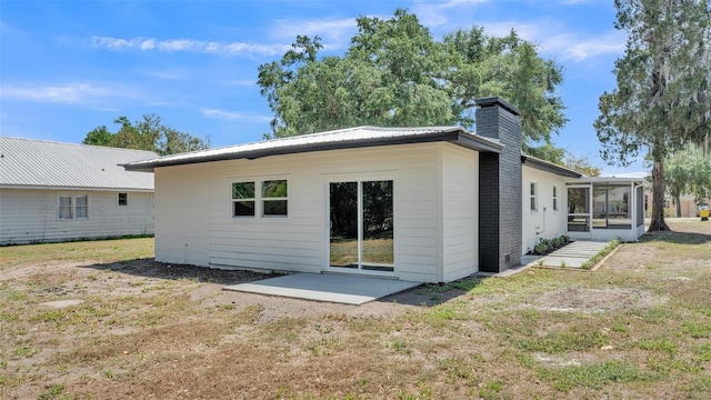 1650 W Mcleod St, Bartow, FL 33830 - back of house featuring a chimney, a sunroom, a patio, and a yard