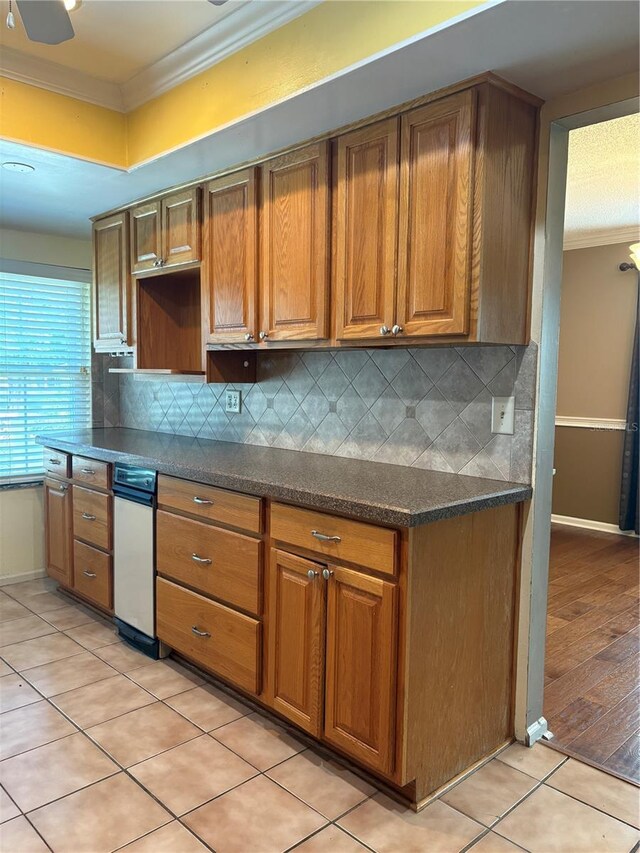 1135 Palace Pl, Lakeland, FL 33813 - kitchen with ornamental molding, backsplash, brown cabinetry, and light tile patterned floors