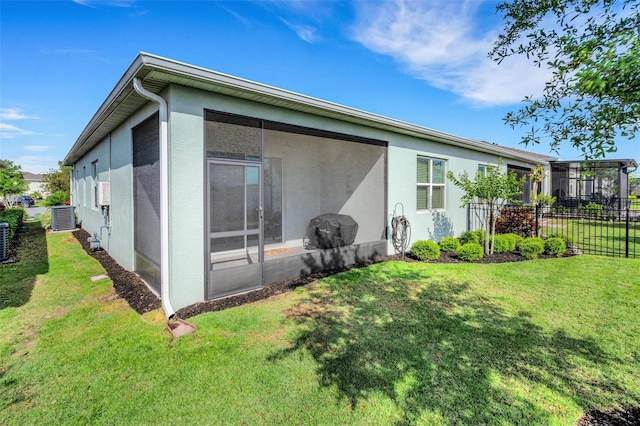 back of house with stucco siding, fence, central AC, and a yard
