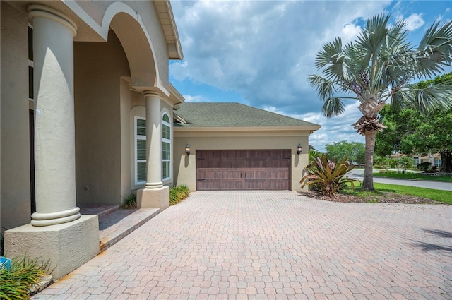 view of home's exterior featuring stucco siding, decorative driveway, and an attached garage