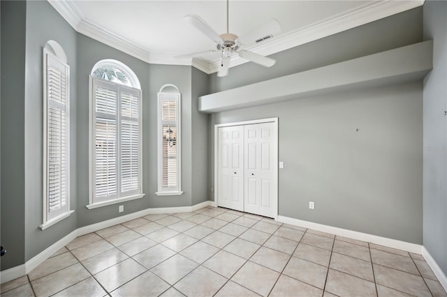 unfurnished bedroom featuring crown molding, light tile patterned floors, a closet, baseboards, and ceiling fan