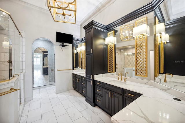 full bathroom featuring ornamental molding, a chandelier, tiled shower, marble look tiles, and two vanities