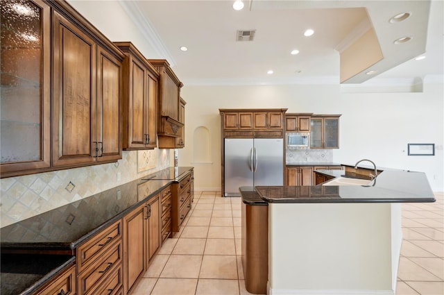 kitchen with built in appliances, a sink, light tile patterned floors, ornamental molding, and a spacious island