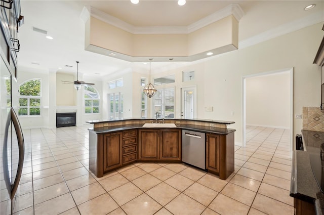 kitchen featuring dishwasher, a sink, a glass covered fireplace, open floor plan, and light tile patterned floors