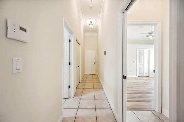 corridor with light tile patterned floors, ornamental molding, and baseboards