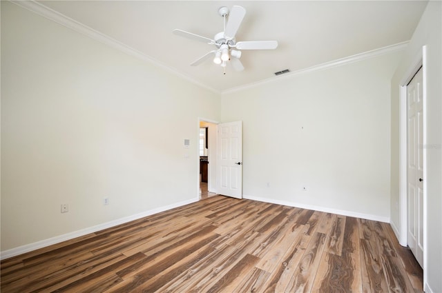 unfurnished bedroom with ornamental molding, baseboards, wood finished floors, a ceiling fan, and a closet