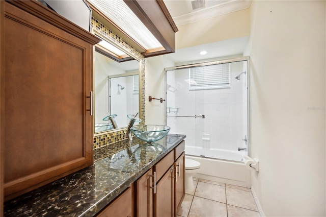 bathroom with tile patterned floors, toilet, vanity, ornamental molding, and combined bath / shower with glass door