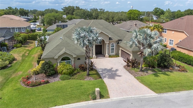 view of front of house featuring decorative driveway, stucco siding, an attached garage, and a front yard