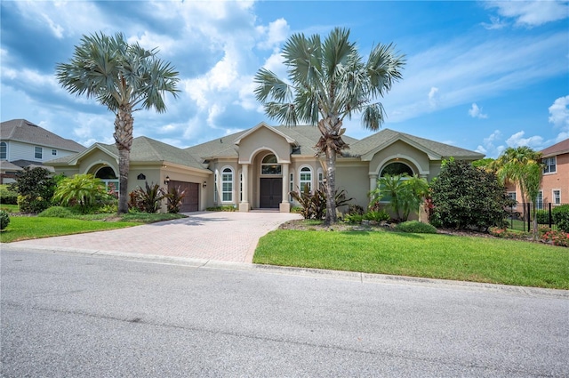 ranch-style house with an attached garage, decorative driveway, and stucco siding