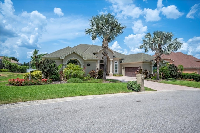 ranch-style house with stucco siding, a garage, a front lawn, and driveway