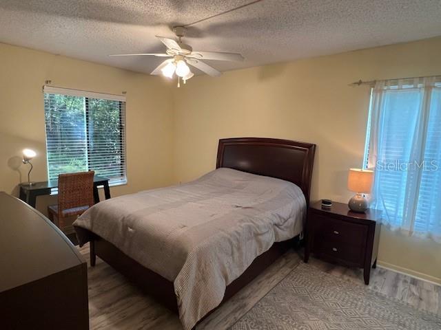 bedroom featuring a ceiling fan, wood finished floors, and a textured ceiling