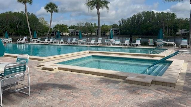pool with fence, a patio area, and a community hot tub