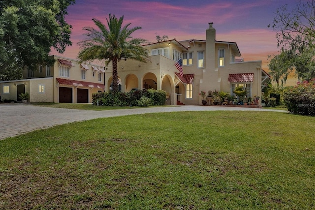 845 E Edgewood Dr, Lakeland, FL 33803 - view of front of house with curved driveway, stucco siding, a garage, and a chimney