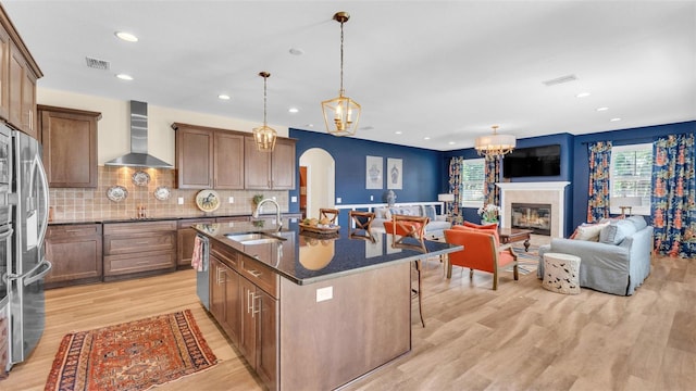 6372 English Creek Dr, Lakeland, FL 33811 - kitchen featuring wall chimney exhaust hood, arched walkways, light wood finished floors, recessed lighting, and a kitchen bar