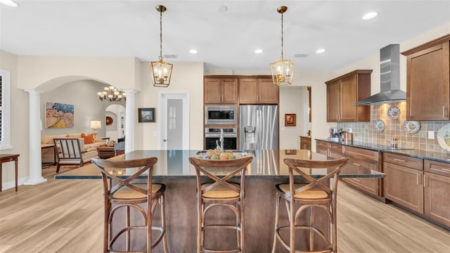 6372 English Creek Dr, Lakeland, FL 33811 - kitchen with appliances with stainless steel finishes, wall chimney exhaust hood, ornate columns, arched walkways, and decorative backsplash