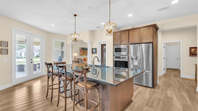 6372 English Creek Dr, Lakeland, FL 33811 - kitchen with stainless steel appliances, light wood-style floors, a breakfast bar area, recessed lighting, and brown cabinets