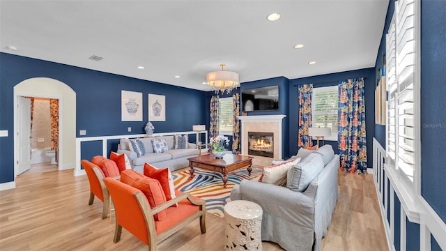 6372 English Creek Dr, Lakeland, FL 33811 - living room with a glass covered fireplace, light wood-type flooring, recessed lighting, a chandelier, and arched walkways