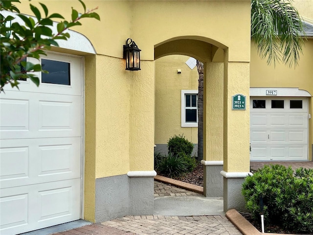 property entrance with stucco siding and a garage