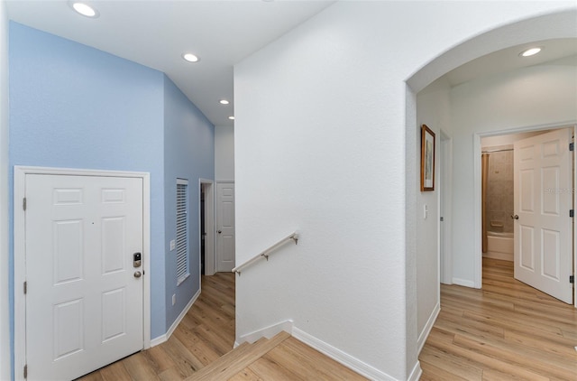 foyer entrance with light wood-style flooring, baseboards, arched walkways, and recessed lighting