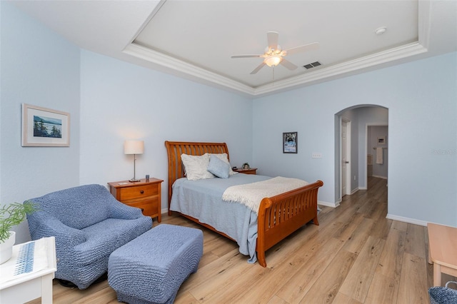 bedroom featuring a ceiling fan, light wood-type flooring, baseboards, a raised ceiling, and arched walkways