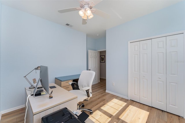 office space with light wood-type flooring, ceiling fan, baseboards, and visible vents