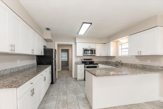 kitchen with stainless steel appliances, a peninsula, white cabinetry, and light stone counters