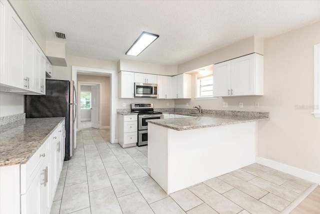 kitchen featuring a peninsula, white cabinetry, visible vents, appliances with stainless steel finishes, and a sink