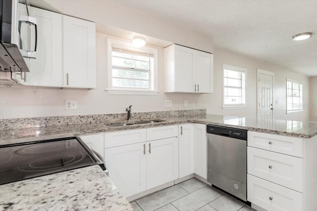 kitchen featuring light tile patterned floors, a sink, a peninsula, white cabinetry, and stainless steel appliances