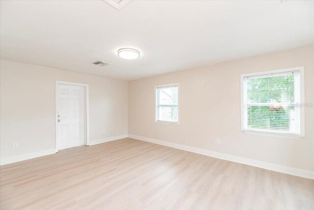 spare room with visible vents, baseboards, and light wood finished floors