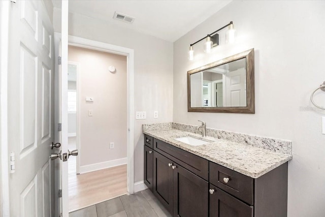 bathroom with vanity, visible vents, baseboards, and wood finished floors