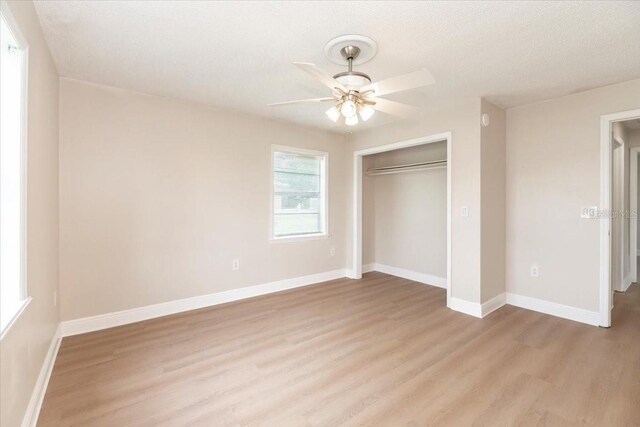unfurnished bedroom with light wood-style flooring, a closet, baseboards, and a ceiling fan