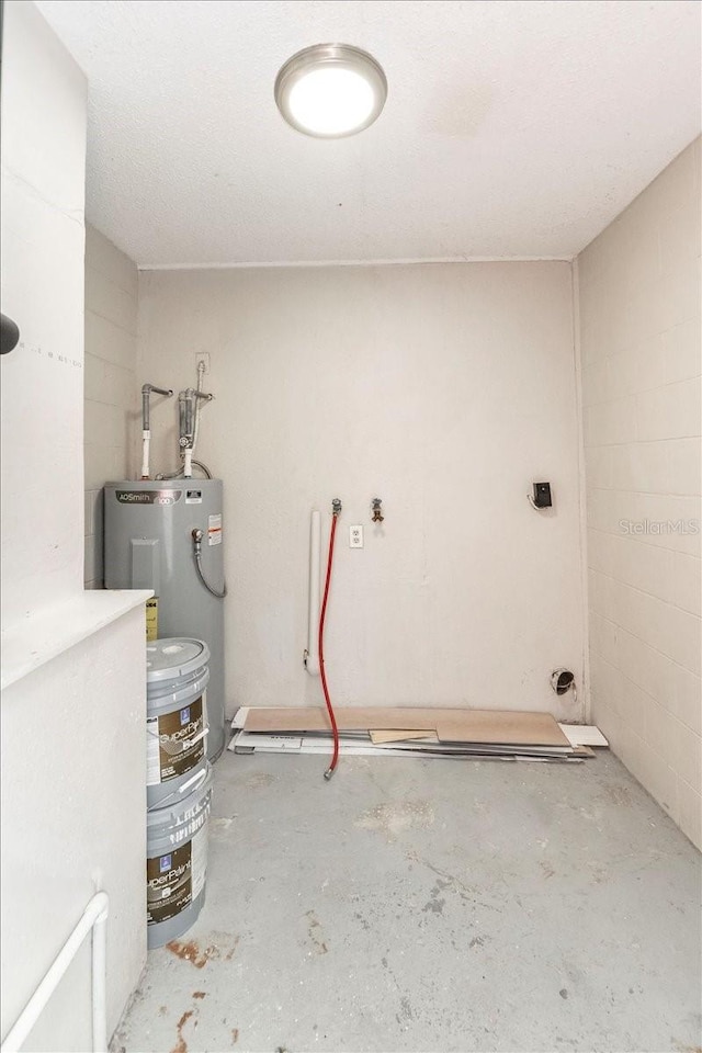 interior space with water heater, laundry area, and concrete block wall