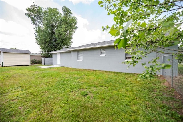 rear view of property with a yard, an outdoor structure, and a storage unit