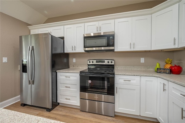 4189 Radford Rd, Bartow, FL 33830 - kitchen featuring appliances with stainless steel finishes, light wood finished floors, white cabinets, vaulted ceiling, and baseboards
