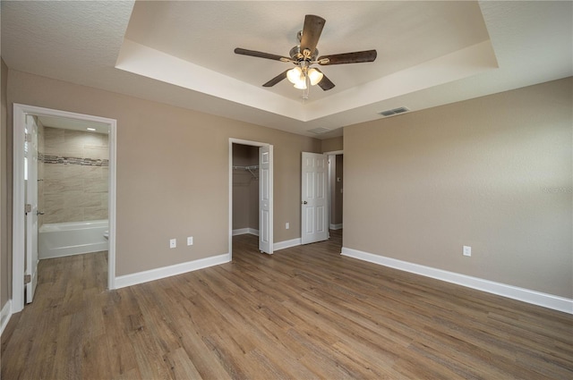 4189 Radford Rd, Bartow, FL 33830 - unfurnished bedroom with a tray ceiling, baseboards, wood finished floors, a closet, and a walk in closet
