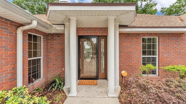 property entrance with brick siding and roof with shingles