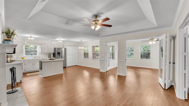 kitchen with stainless steel fridge with ice dispenser, light countertops, a raised ceiling, light wood finished floors, and ceiling fan with notable chandelier