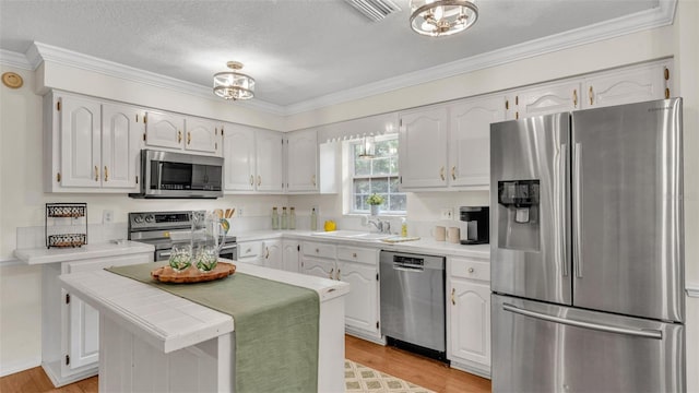 kitchen with light wood-type flooring, white cabinetry, visible vents, appliances with stainless steel finishes, and a sink