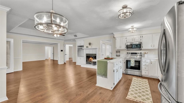 kitchen with a fireplace, a chandelier, appliances with stainless steel finishes, light countertops, and open floor plan