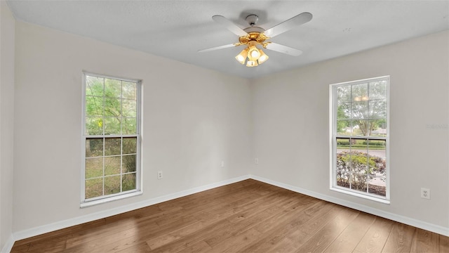 empty room featuring baseboards, wood finished floors, and a healthy amount of sunlight