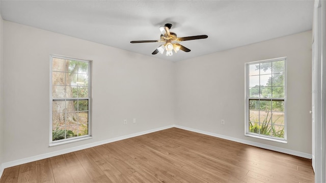 empty room with wood finished floors, baseboards, and a ceiling fan