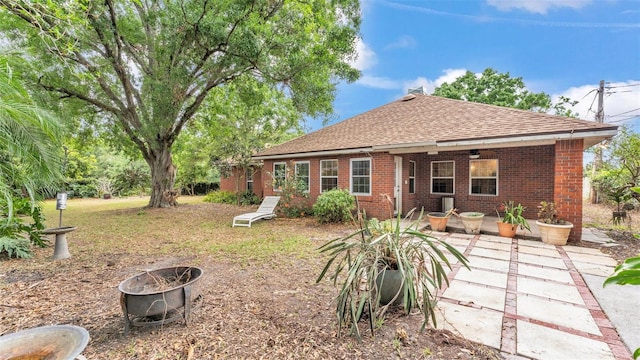 back of house with an outdoor fire pit, roof with shingles, a patio area, and brick siding