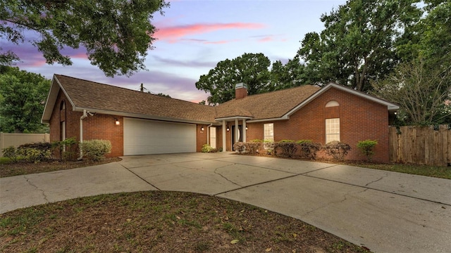 ranch-style house featuring fence, brick siding, an attached garage, a chimney, and driveway