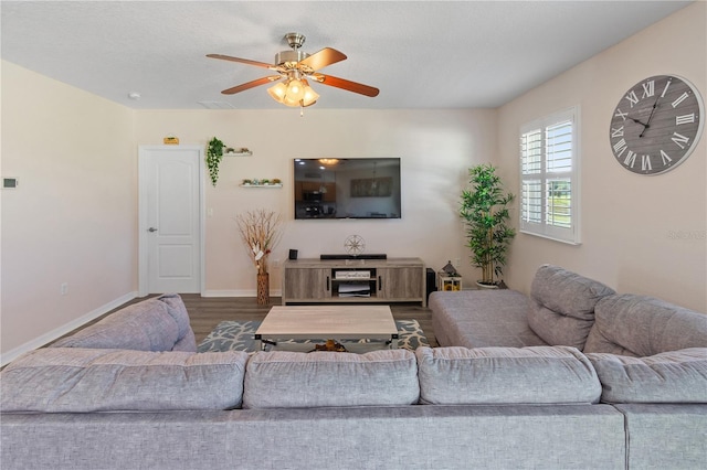 living area with dark wood-style flooring, visible vents, baseboards, and a ceiling fan