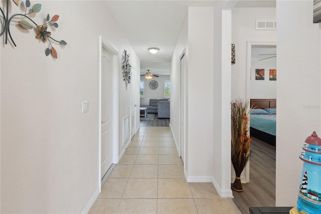 corridor featuring light tile patterned flooring, baseboards, and visible vents