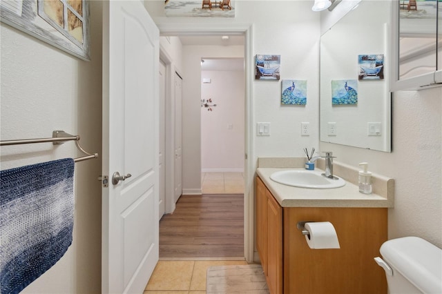 half bathroom featuring tile patterned floors, vanity, and toilet