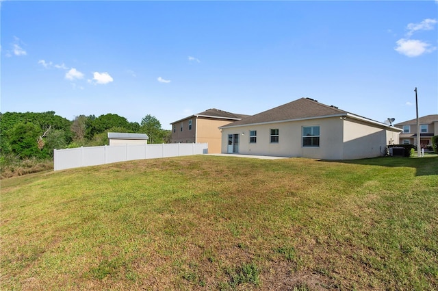 rear view of property with a patio area, stucco siding, fence, and a lawn