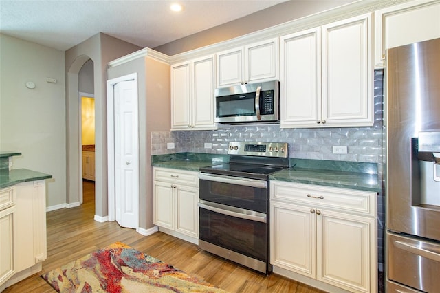 6626 Royal Forest Dr, Lakeland, FL 33811 - kitchen featuring decorative backsplash, light wood-type flooring, arched walkways, and stainless steel appliances