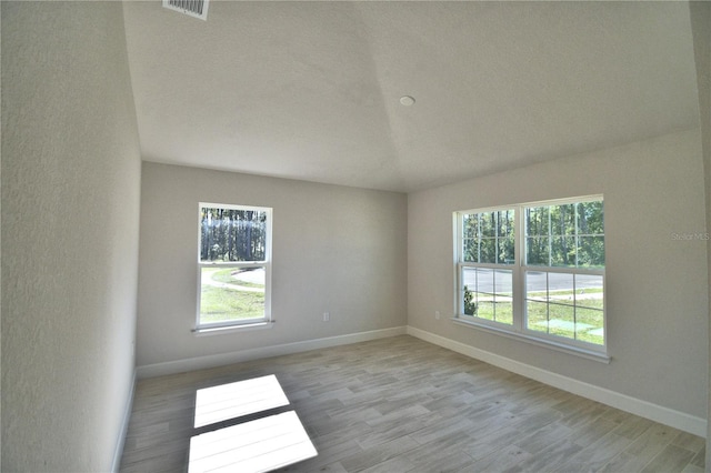 empty room featuring baseboards, visible vents, and wood finished floors