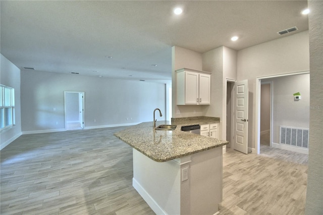 kitchen featuring dishwasher, a sink, light stone countertops, and visible vents
